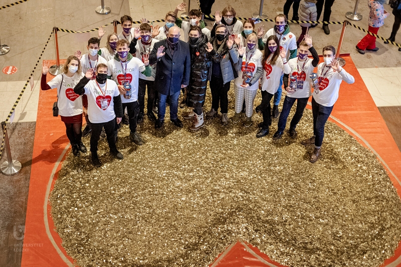 Students from the Student Science Club Inwestor and the University of Lodz authorities standing in front of a huge heart made of gold coins