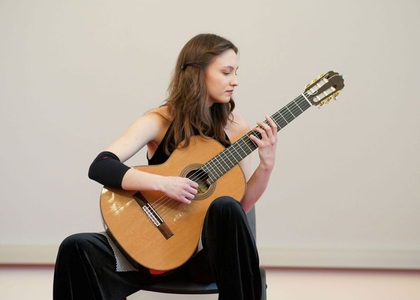 Kalina Polańska who is sitting and playing the guitar