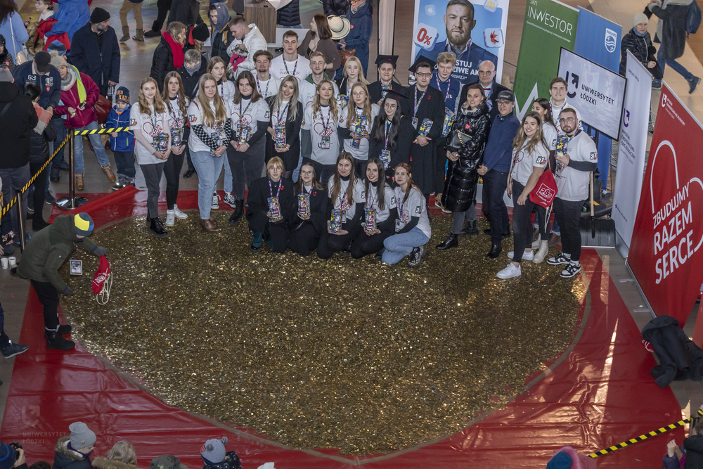 The University of Lodz students from the Student Science Club Inwestor standing with the University of Lodz authorities next to a heart made of gold coins